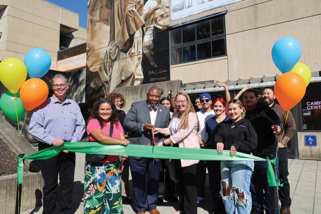 President Timmons helps cut the ribbon unveiling a new campus mural.