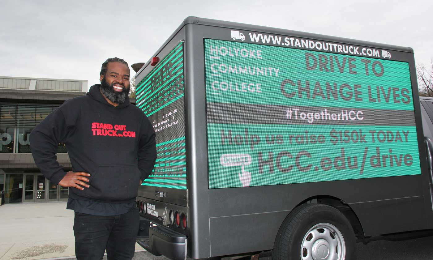 Myke Connolly stands up beside his Stand Out Truck in front of the HCC Campus Center