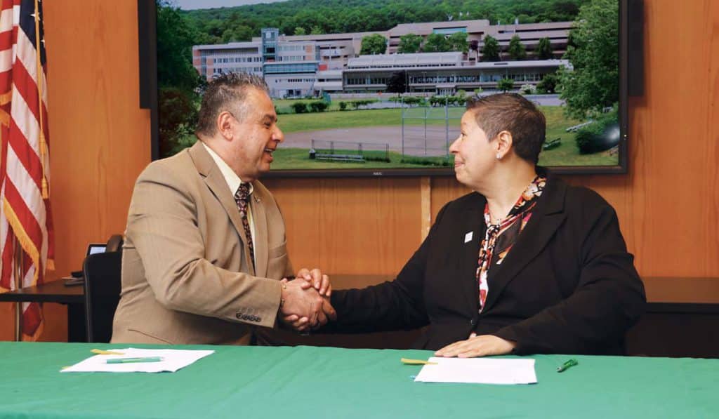 AIC President Hubert Benitez and then-HCC President Christina Royal shake hands after signing a “historic” agreement in April 2023.