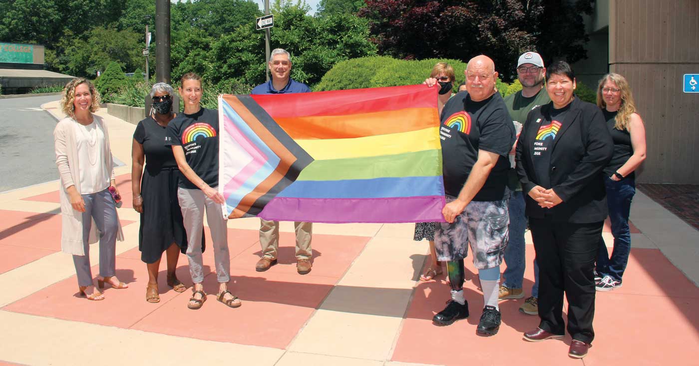 President Christina Royal and assorted HCC staff members hold up the Pride flag before it was hoisted up the flag pole in recognition of Pride Month in June.