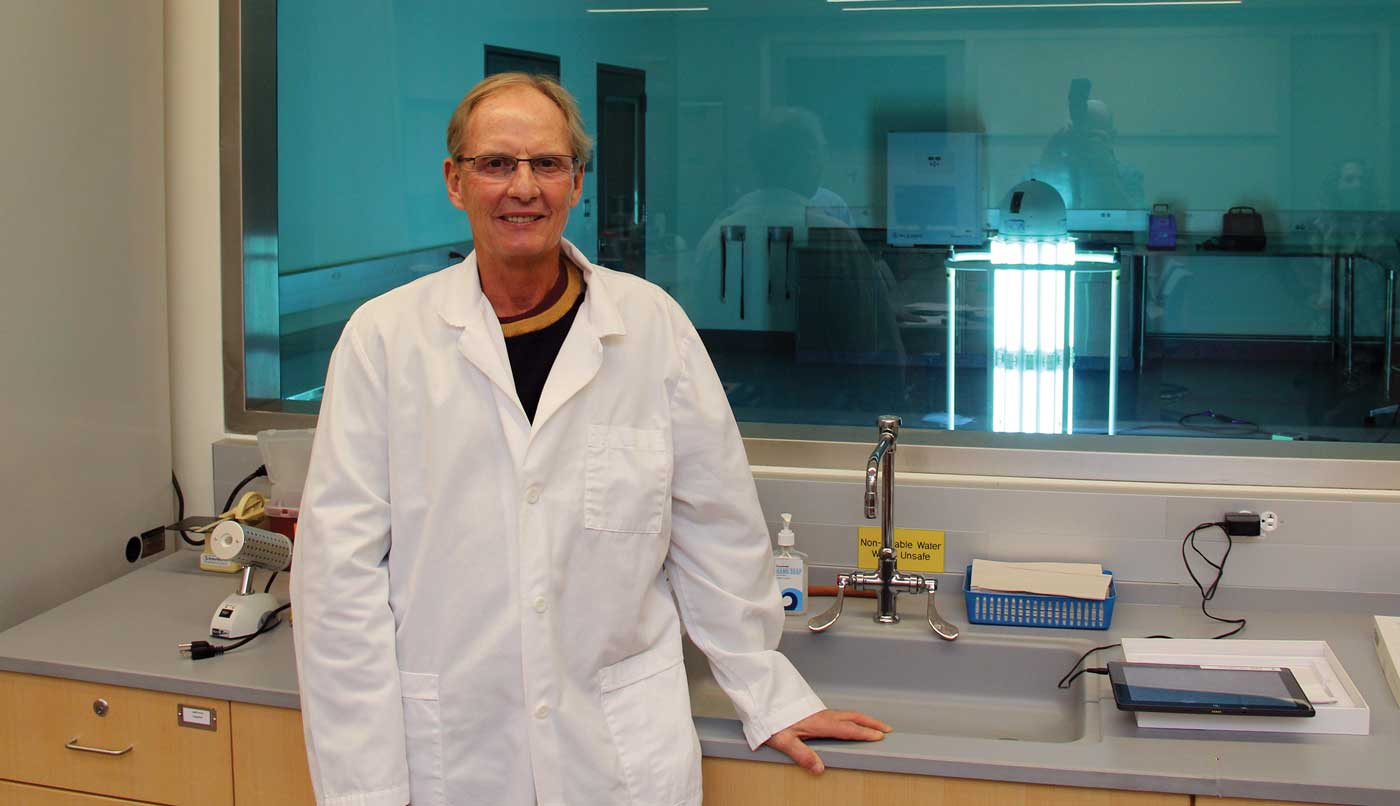 Steve Richter ’75 stands outside the cleanroom in HCC’s Center for Life Sciences while Thor goes to work cleaning up.