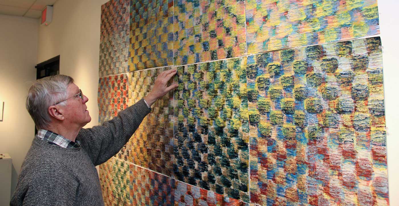 HCC professor Frank Cressotti installs pieces from his exhibit, “Pages: Paintings on Newspaper” in the Taber Art Gallery.