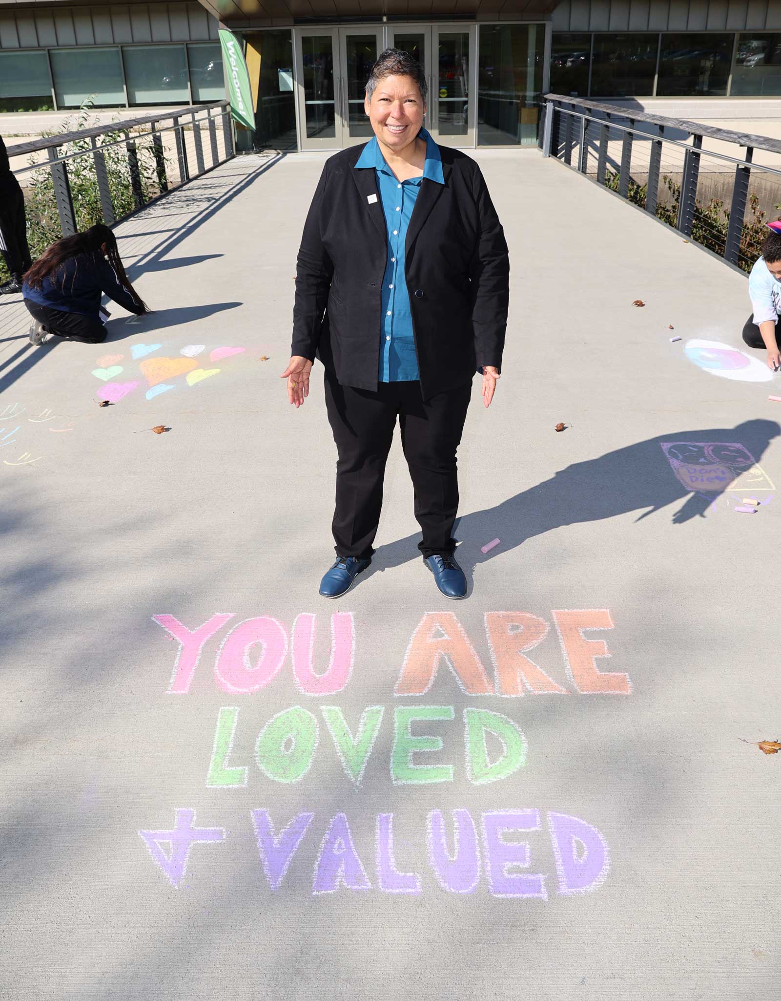 October 2022: President Royal stands outside the Campus Center in support of students painting a rainbow crosswalk leading to the parking lot.