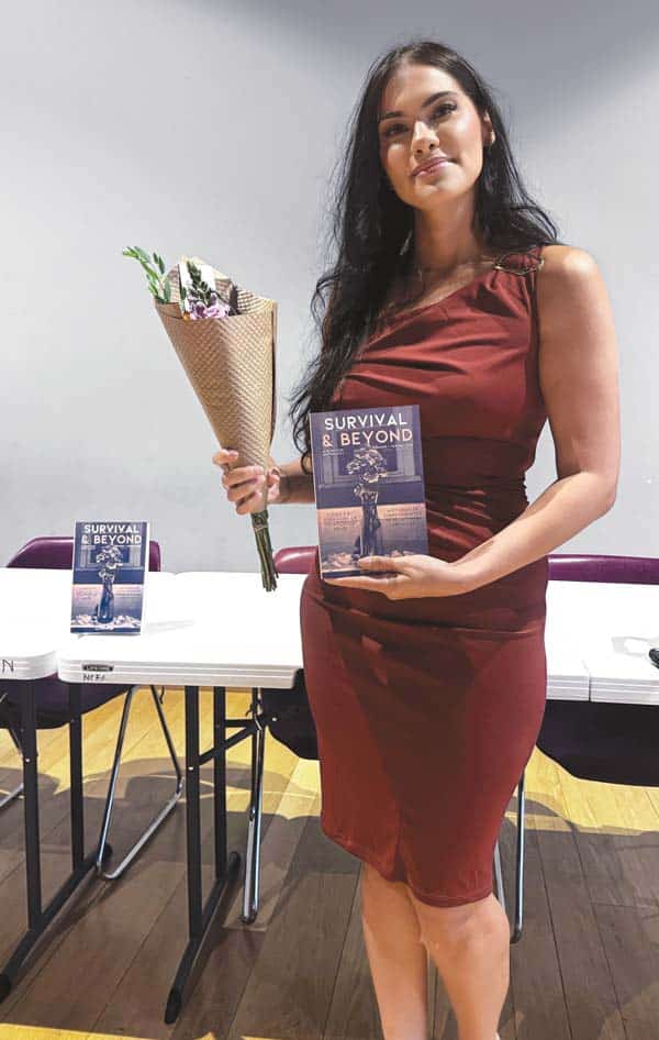 Mydalis Vera ’11 holds a copy of the book, Survival and Beyond, an anthology that includes her poem, “The House.”