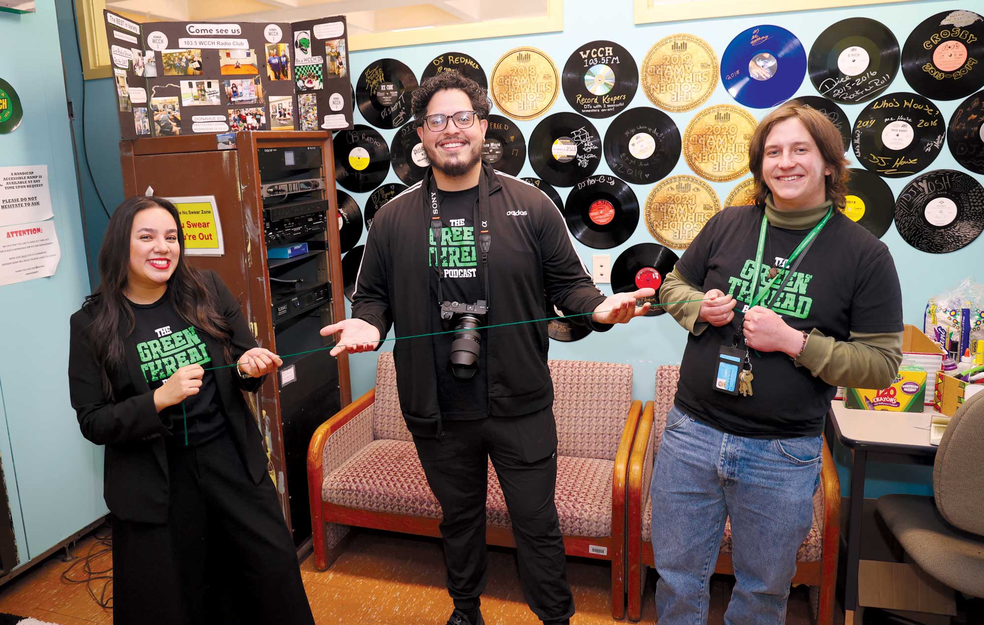 Co-hosts Natalia Castagno, left, Patrick LaBelle, right, and alumni guest Louis Burgos ’14, ’18, hold a green string symbolizing the theme of the podcast.