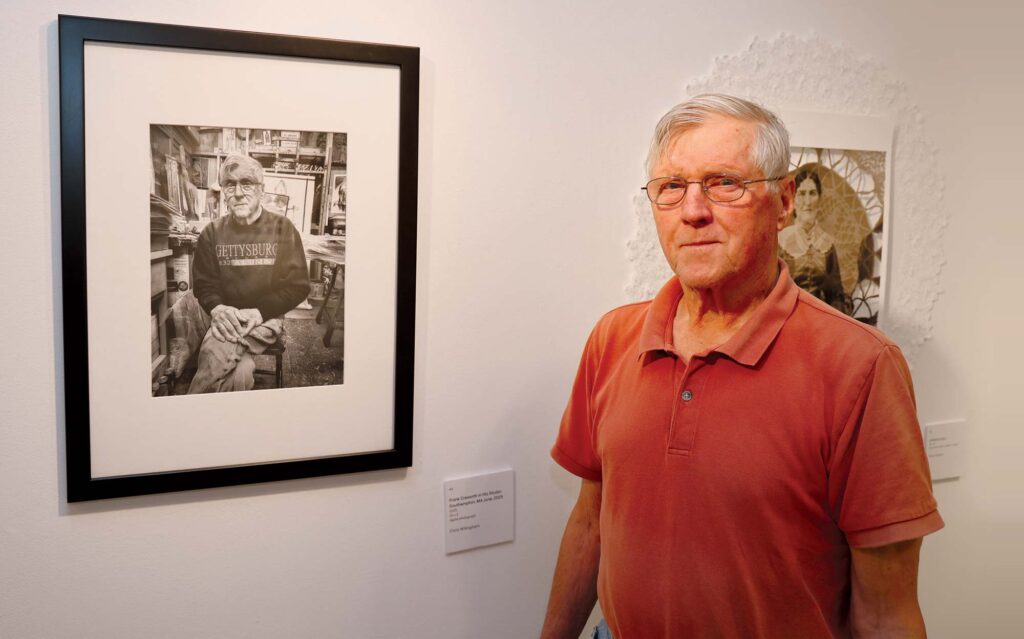 Retired visual art professor Frank Cressotti stands next to a portrait of himself during “Milestone,” the Taber’s fall 2025 anniversary exhibition.