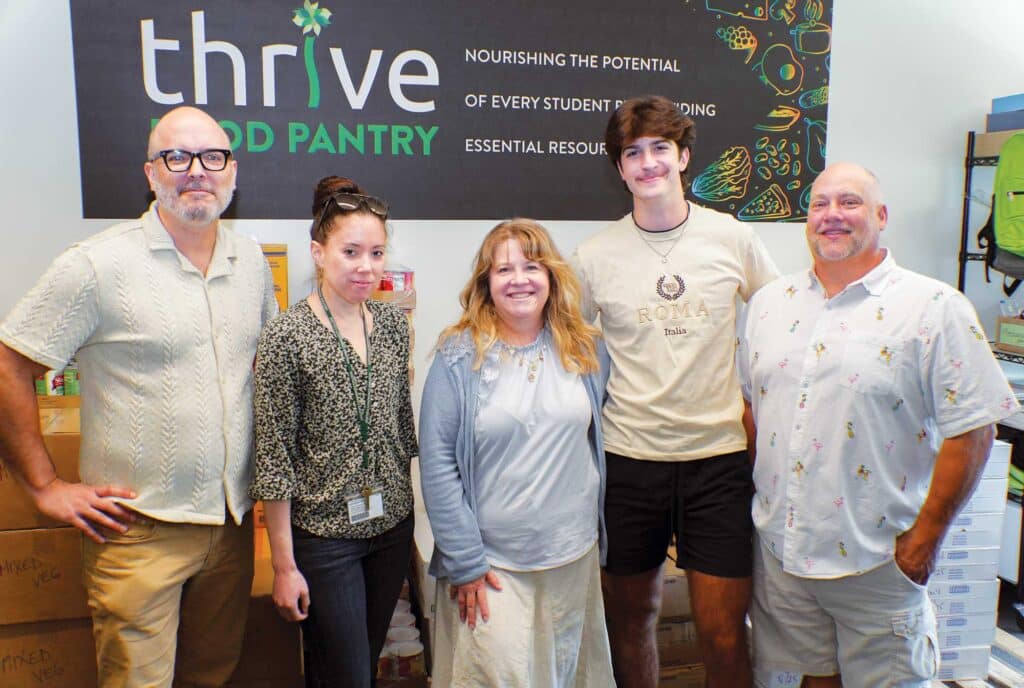 Thrive coordinator Ben Ostiguy, left, food pantry coordinator Elizabeth Eastman, and Sheila Dion ’93, center, with Dion’s son John and her fiancé Dean, during an August 2025 visit to HCC.