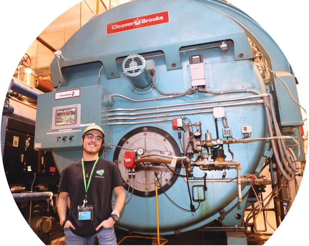 Barney Garcia ’24 stands next to boiler 3 in the HCC Facilities building.